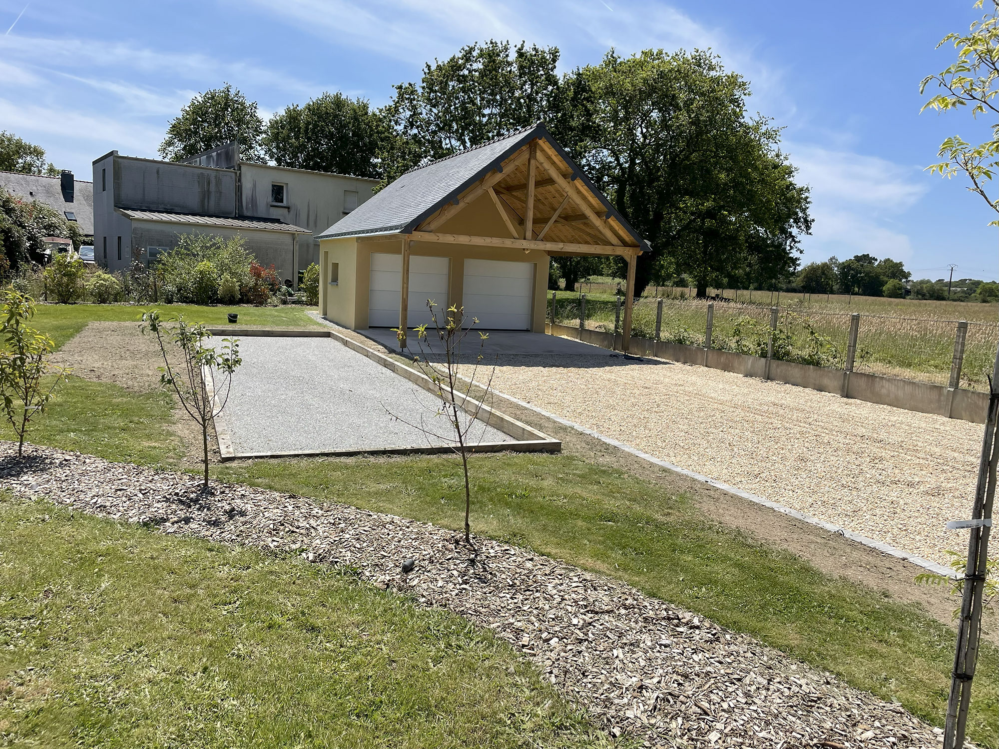 Garage bois avec auvent et allée gravillonnée aménagée par Breiz Paysage