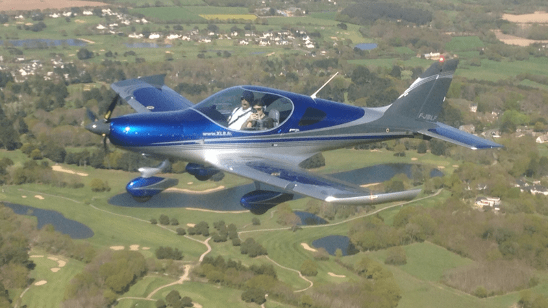 Avion en vol au-dessus de la campagne avec deux passagers lors d'un baptême de l'air à La Baule