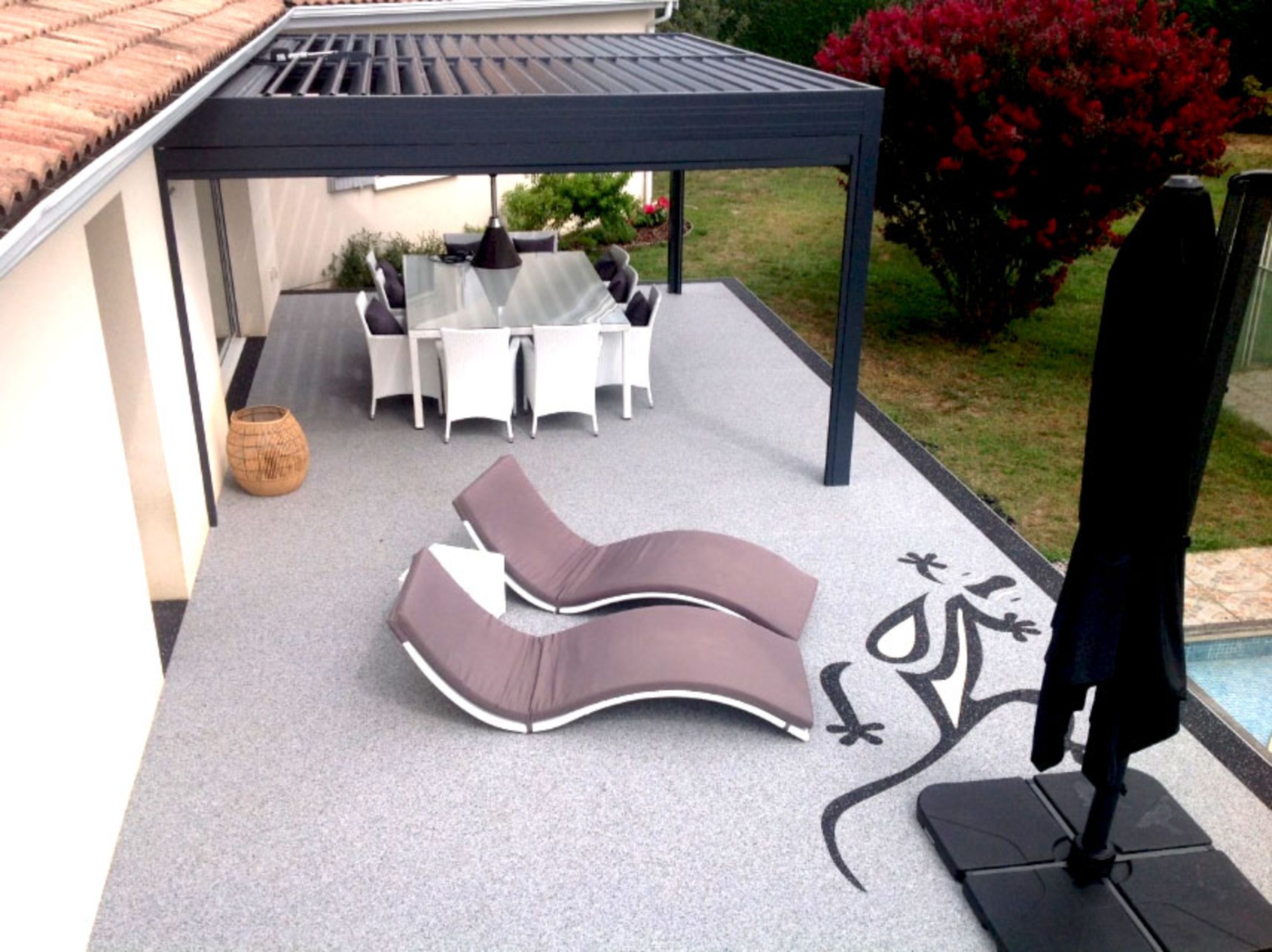 Terrasse en résine drainante grise avec motif de gecko et mobilier de jardin
