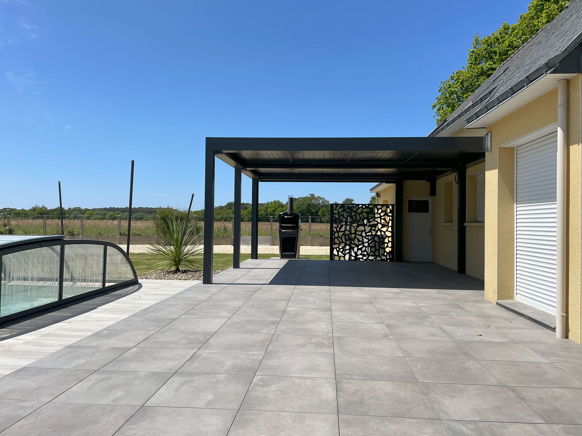 Terrasse en carrelage gris avec pergola aluminium et piscine aménagée par Breiz Paysage