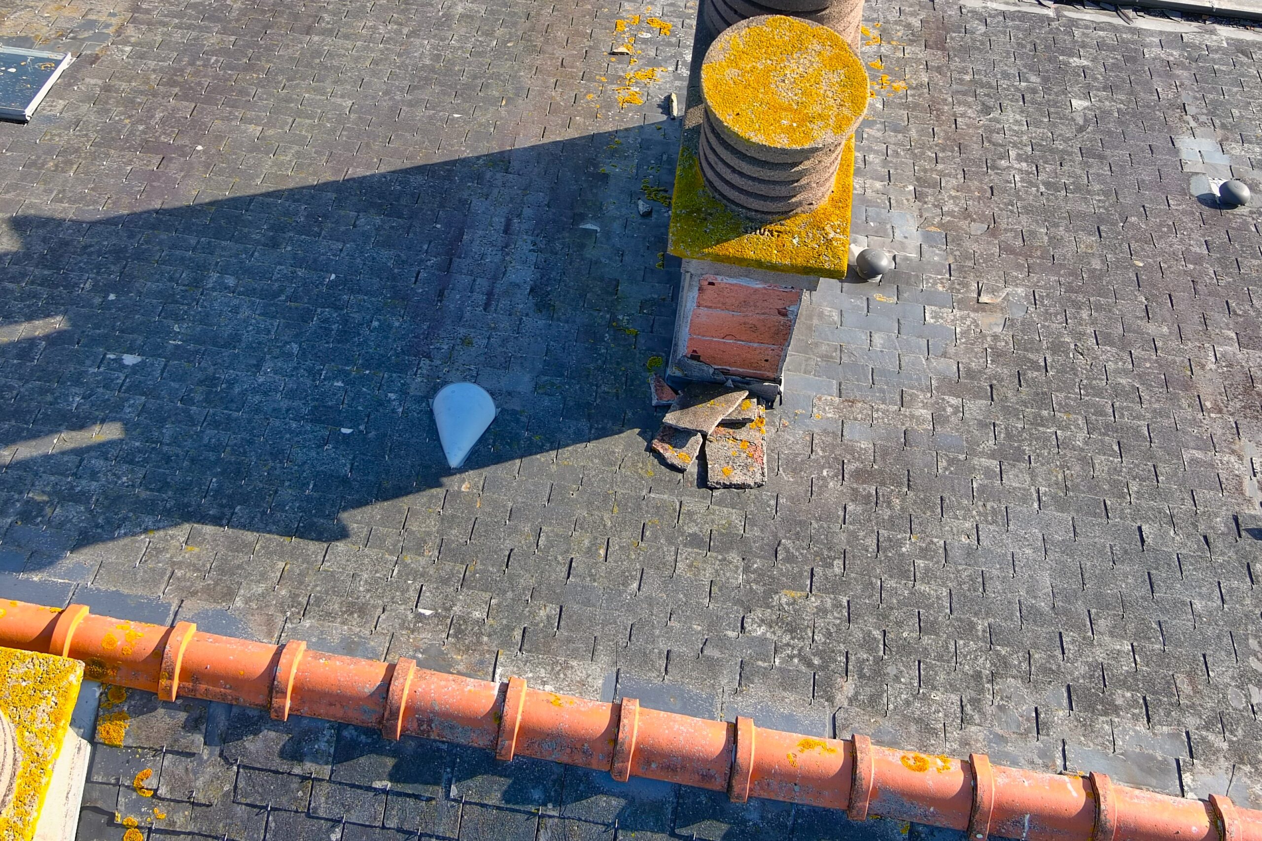Détail d'une cheminée et de tuiles endommagées sur une toiture repéré grâce à la photographie aérienne
