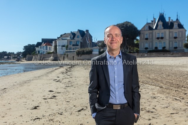Fondateur du cabinet Côte d'Amour Patrimoine posant sur la plage face à une villa et un château de Pornichet
