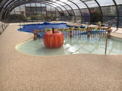Sol en résine drainante autour d'une piscine intérieure avec véranda