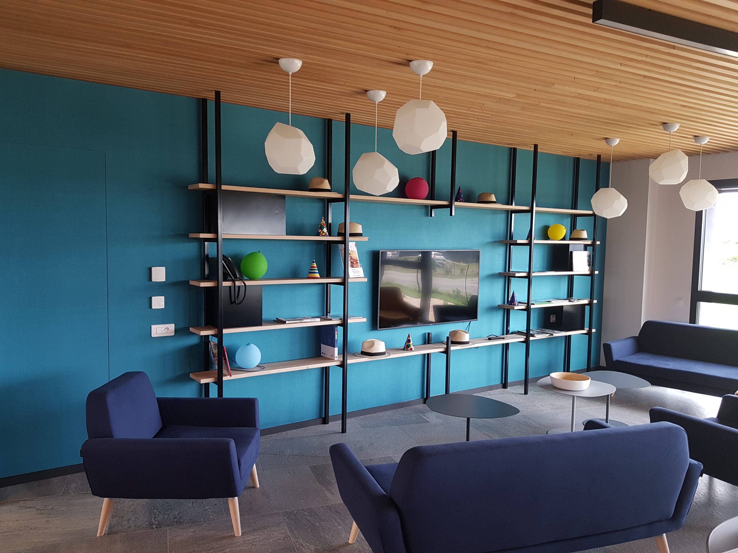 Espace d'accueil avec bibliothèque bleue conçu par Tual Agencement